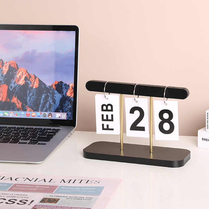 Desktop wooden flip calendar on black base, month card FEB and date 28 on stands