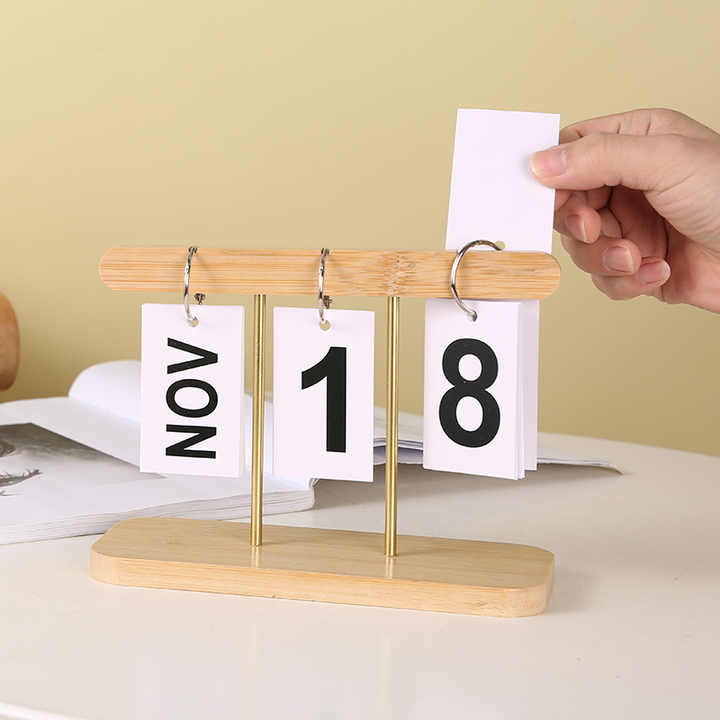 Desktop wooden flip calendar with light wood base, month cards NOV and 18 with brass stands