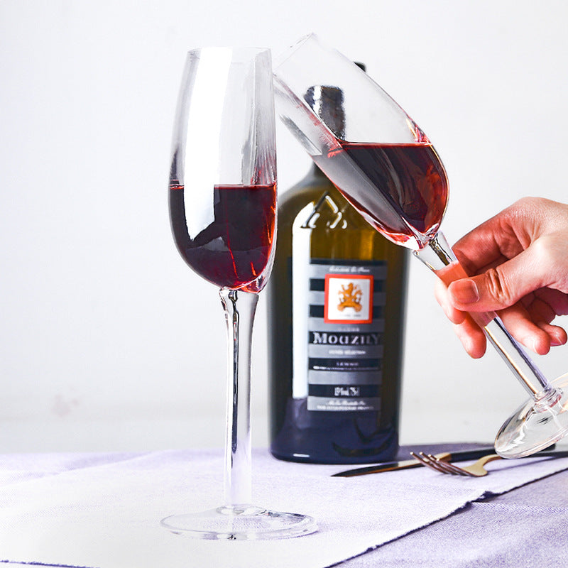 Crystal wine glass being filled with red wine, clear half-round bowl and long stem.