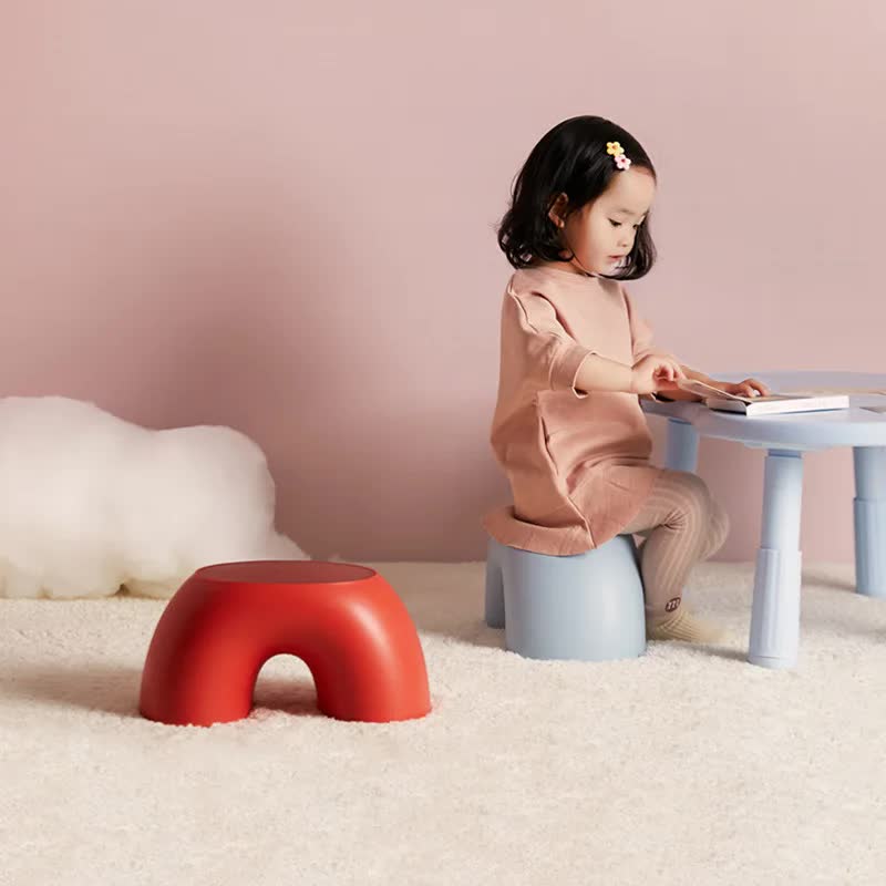 Red round plastic footstool with arched cutout seat, low curved shape for sitting