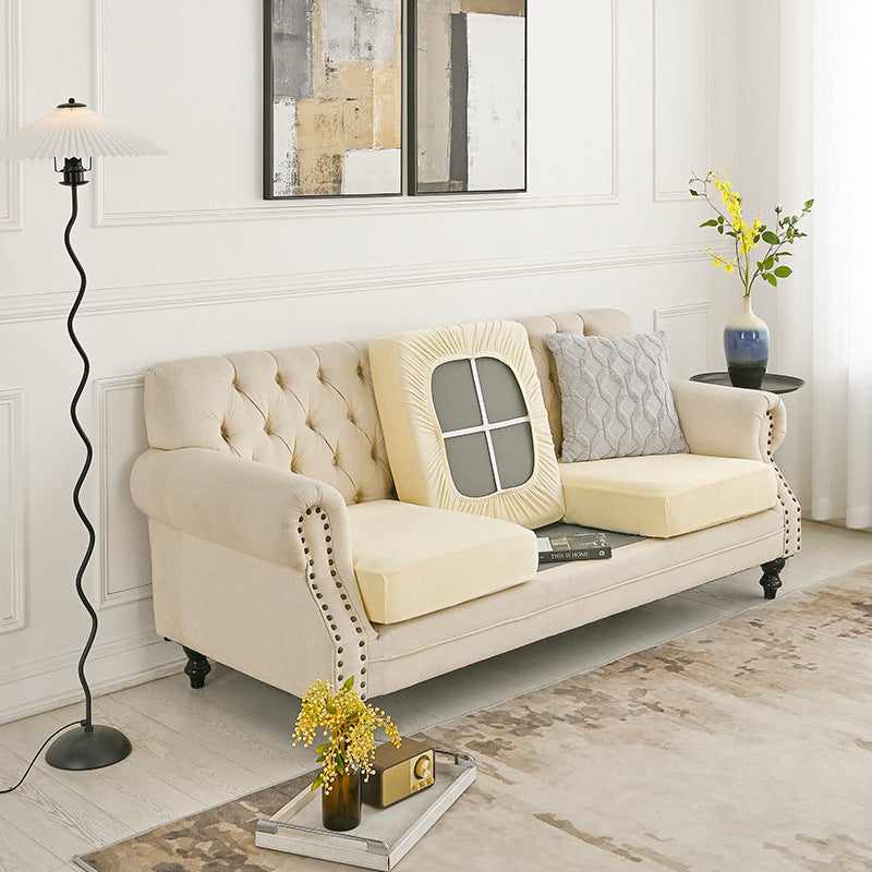 Beige polyester sofa cover fitted over a tufted 2-seater sofa with armrests