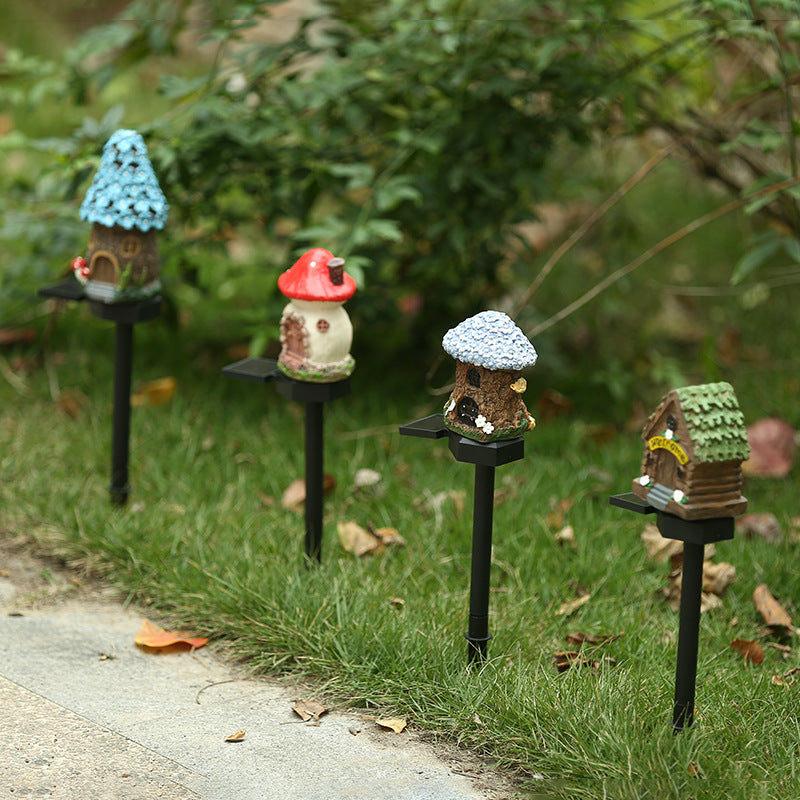 Solar garden stake lights with small resin houses on black spikes and blue roofs