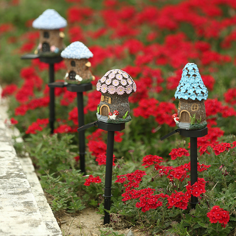 Solar garden stake light with a resin house shade, blue roof, and black stake