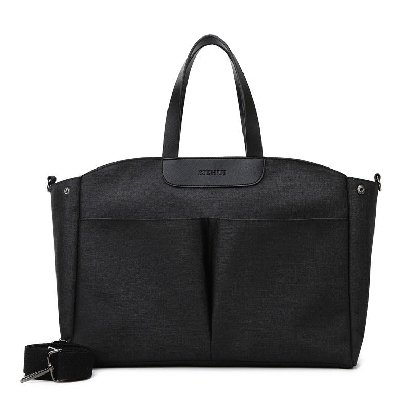 Black diaper tote bag with top handles and front zip pocket; includes small wrist strap