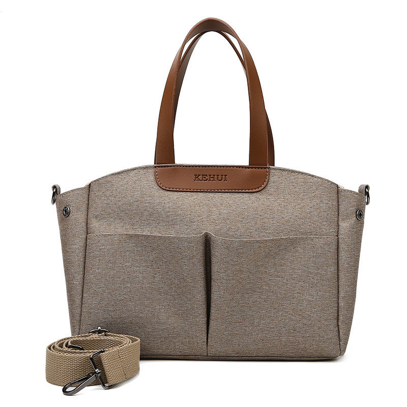Khaki diaper bag tote with top handles, side grommets, and zip front organizer pockets