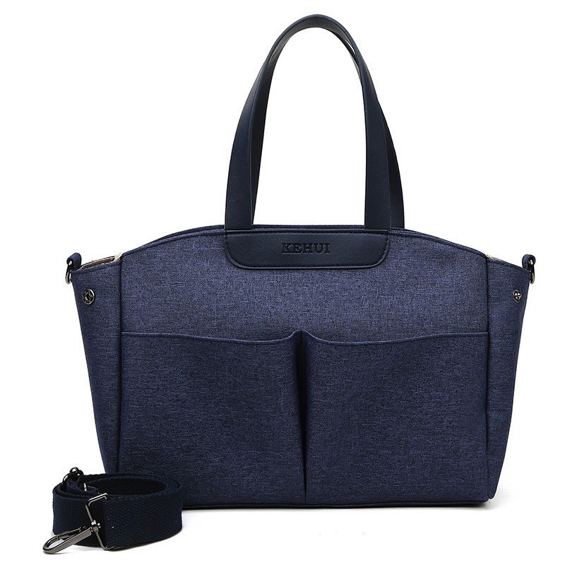 Dark blue diaper tote bag with top handles, front zip pocket, and included wrist strap