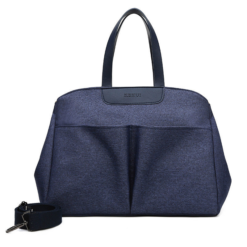 Dark blue diaper tote bag with top handles and front zip pocket; includes crossbody strap.