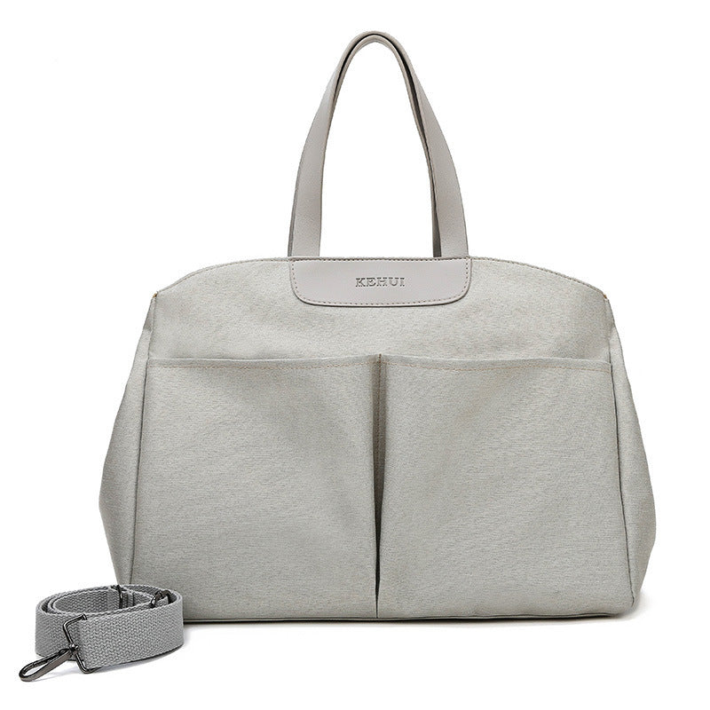 Grey diaper tote bag with wide handles, front panel seams, and attached wrist strap