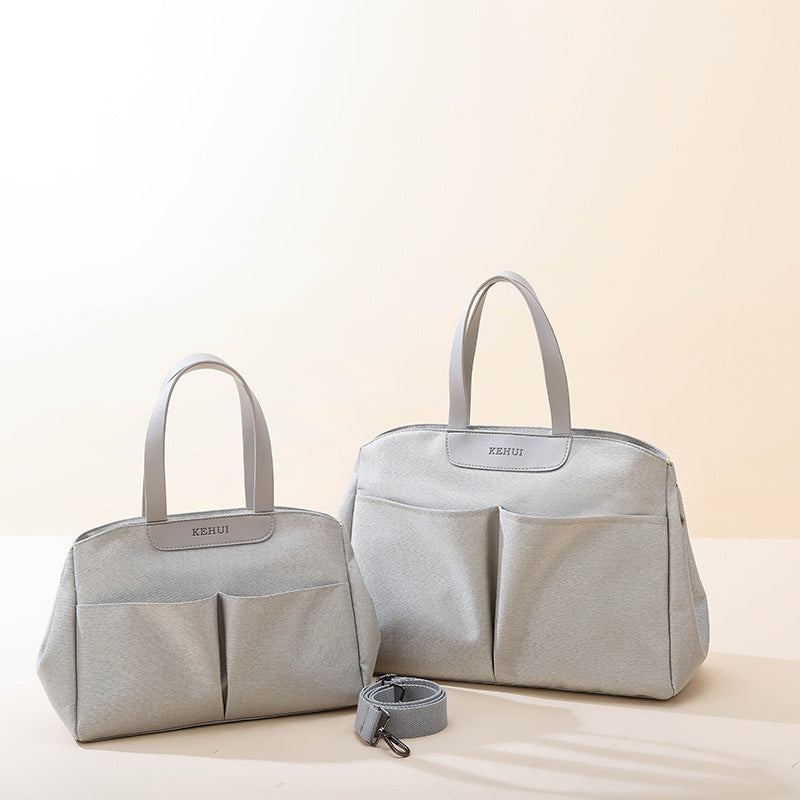 Two gray diaper bags with top handles, side pockets, and front center seam