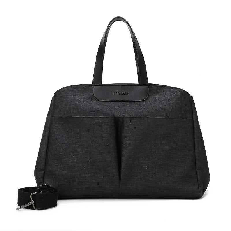 Black large diaper bag tote with top handle, front pocket panels, and shoulder strap