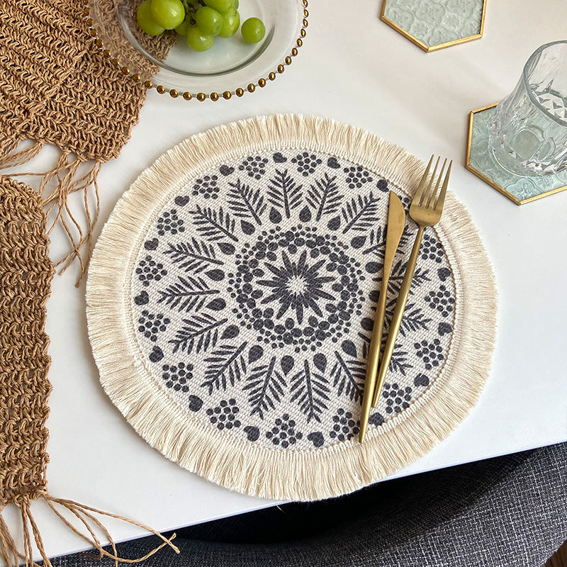 Beige woven cotton round placemat with navy geometric print and white tassel fringe