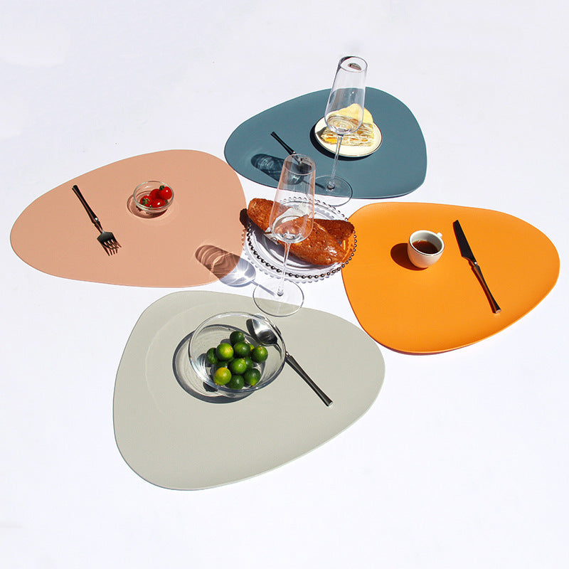 Assorted triangular placemats in blue, teal, orange, and tan with tableware on top
