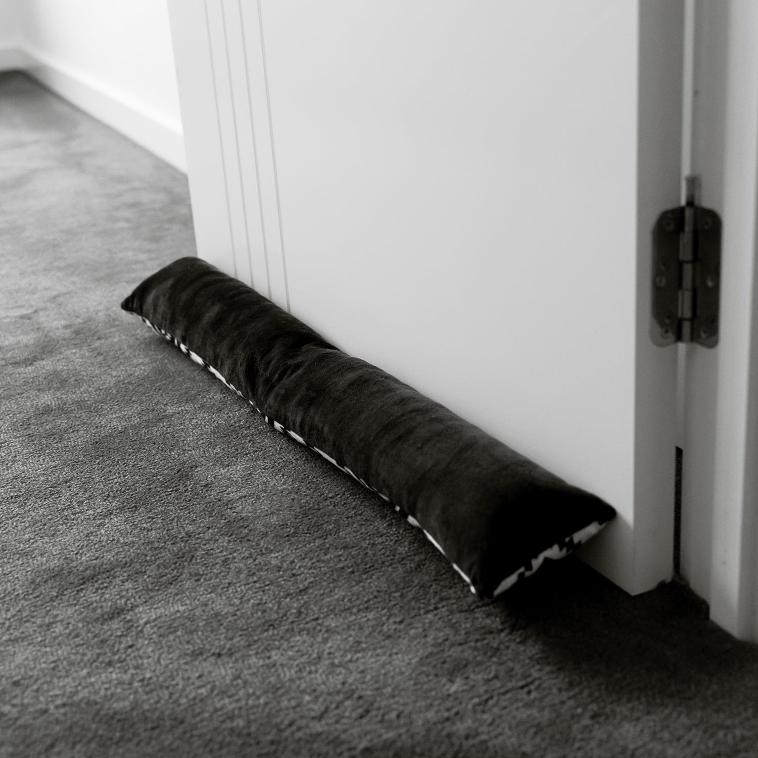 Black draft door stopper cushion with sewn edges for blocking door drafts