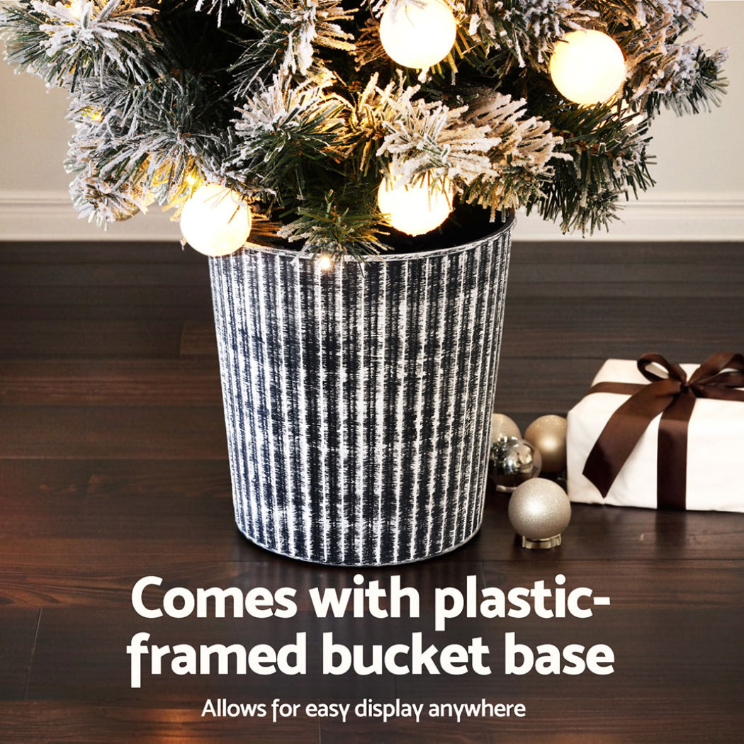 Snowy Christmas tree with warm white LED bulbs in a striped ribbed bucket planter