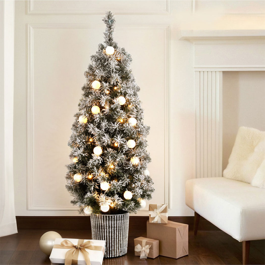 Potted snowy Christmas tree with warm white globe lights and white bauble ornaments