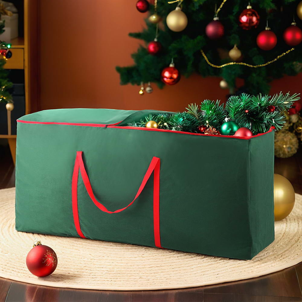 Green Christmas tree storage bag with red handles, filled with ornaments
