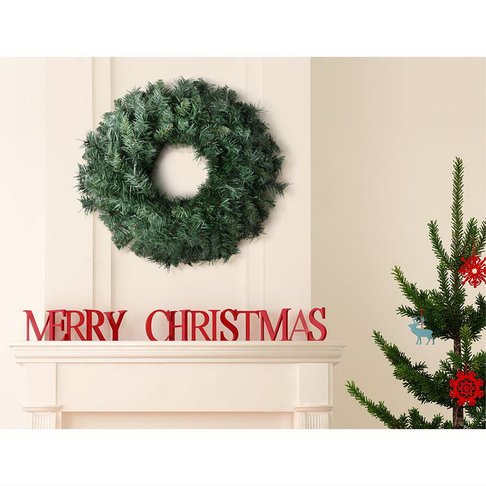 Green artificial Christmas wreath hanging on a door, round pine decoration
