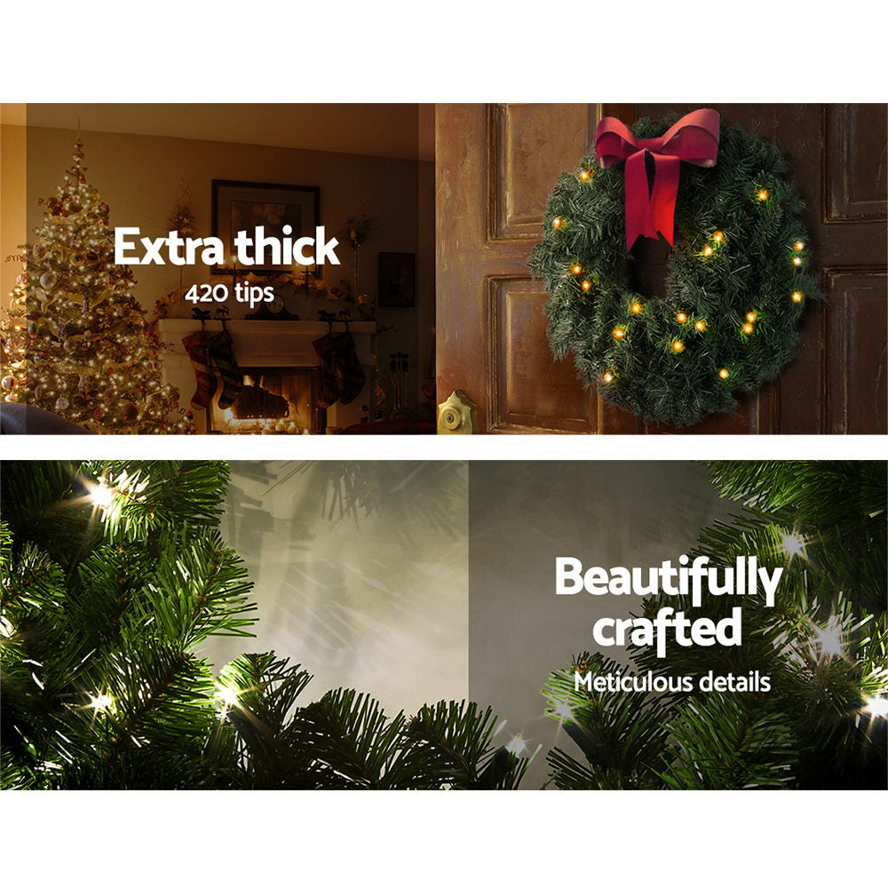 Green pine Christmas wreath with red ribbon bow and warm white lights