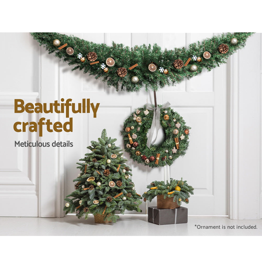Lighted green Christmas garland with brown and white ornaments along the swag