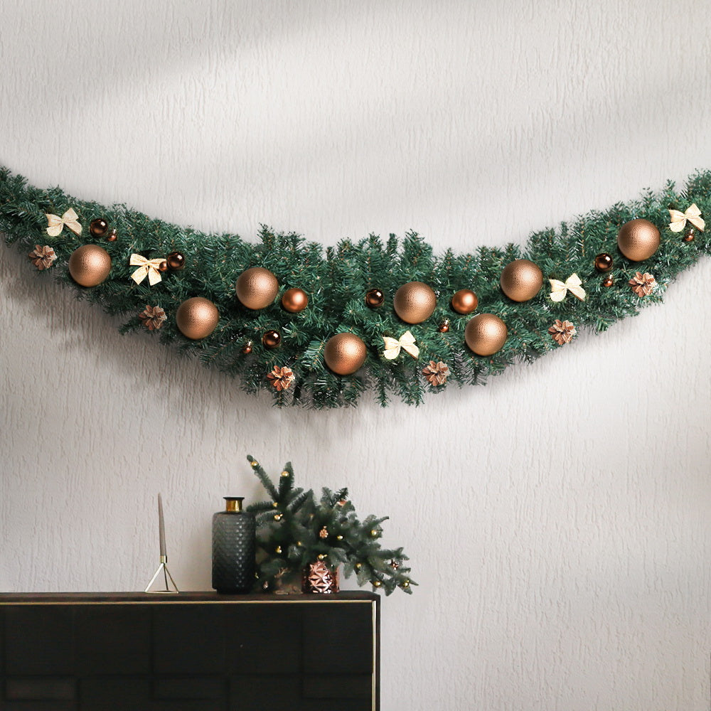 Decorated green Christmas garland with bronze baubles, bows, and pine foliage