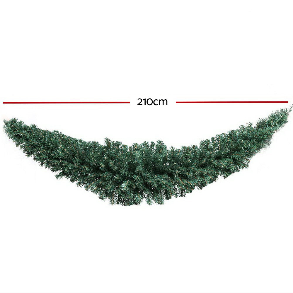 Green Christmas garland with dense pine branches in a curved swag