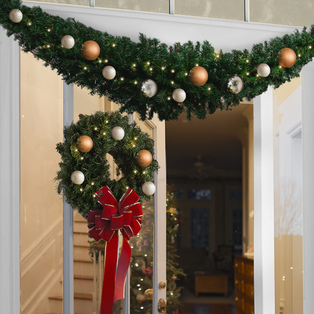 Christmas garland with pine branches, warm fairy lights, copper and white baubles
