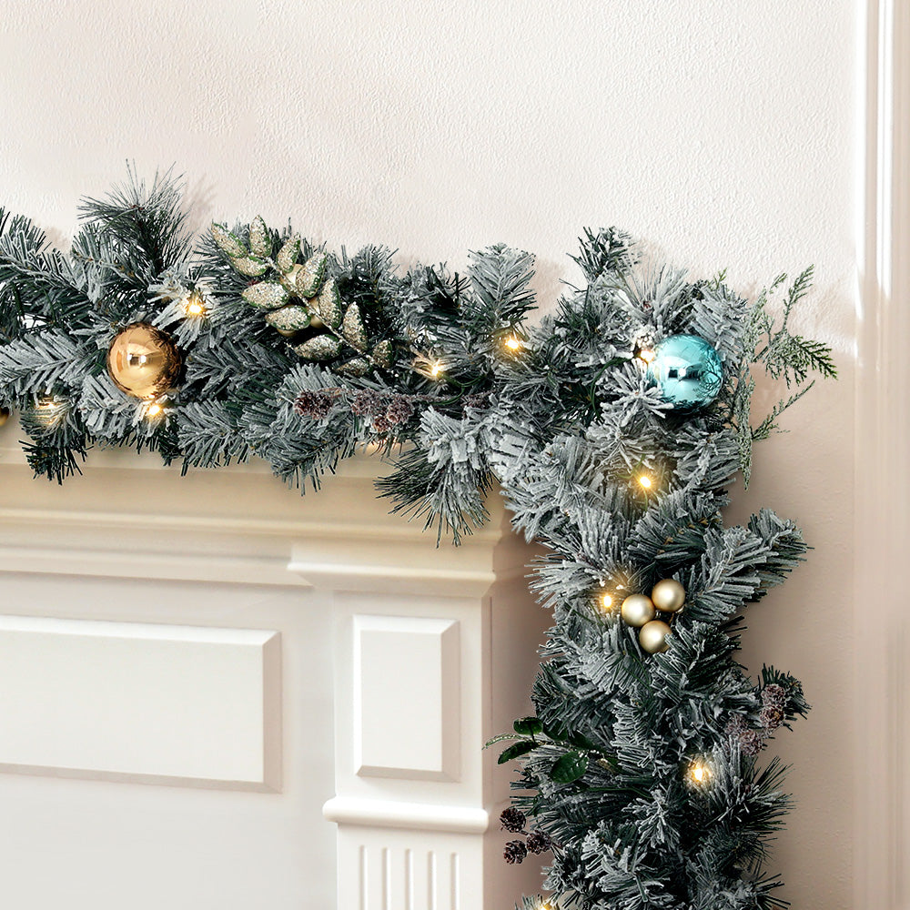 Flocked snowy Christmas garland with warm LED lights and gold, blue baubles
