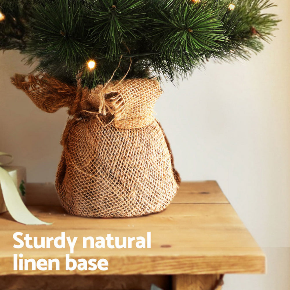 Burlap linen base holding warm LED-lit dark green Christmas tree branches