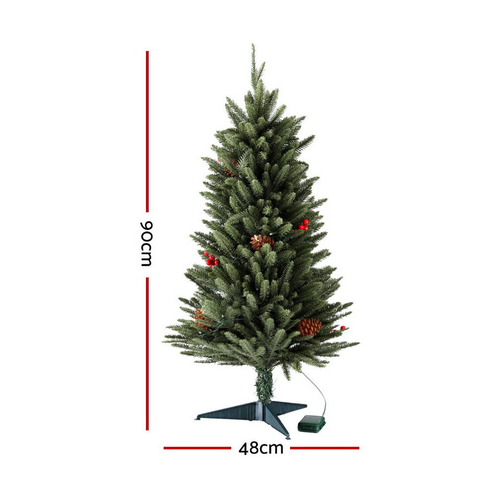 Mini Christmas tree with green branches and warm LED lights, pinecone berry ornaments on stand