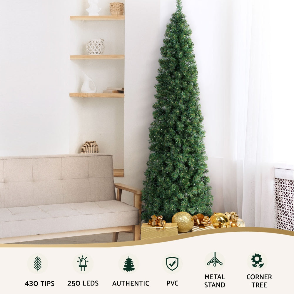 Lighted green corner Christmas tree with warm lights beside sofa and gifts