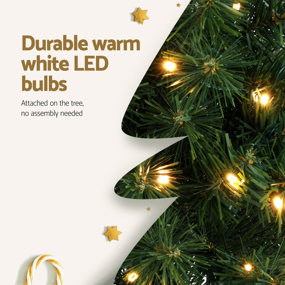 Green artificial Christmas tree branch with warm white LED bulbs glowing