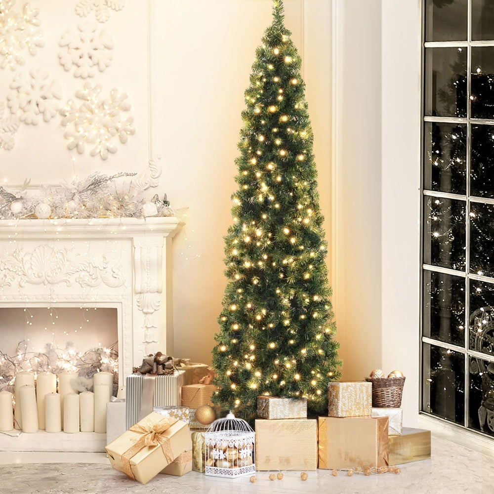 Lighted green artificial Christmas corner tree standing next to wrapped gifts