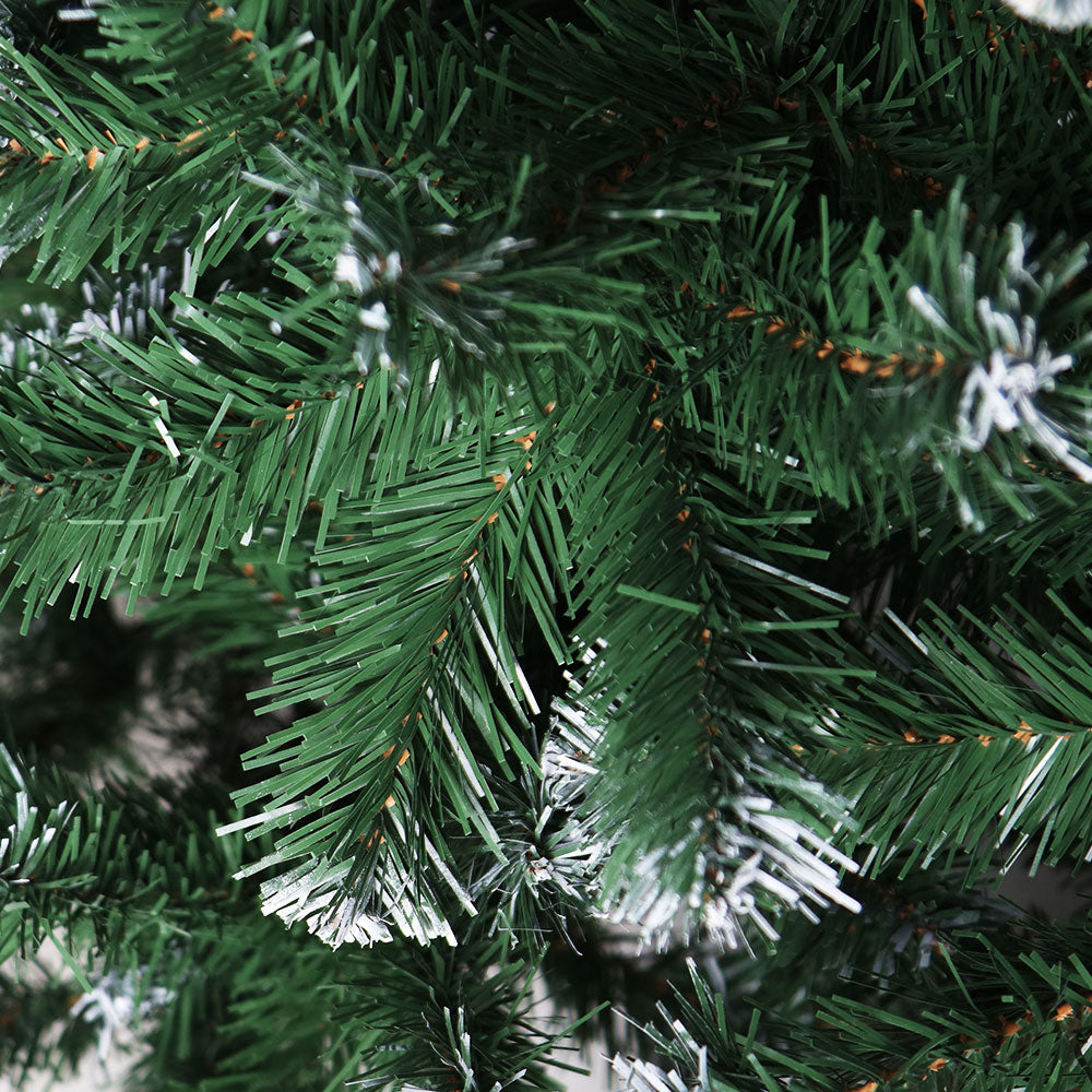 Artificial Christmas tree branch close-up with dark green needles and white snowy tips.