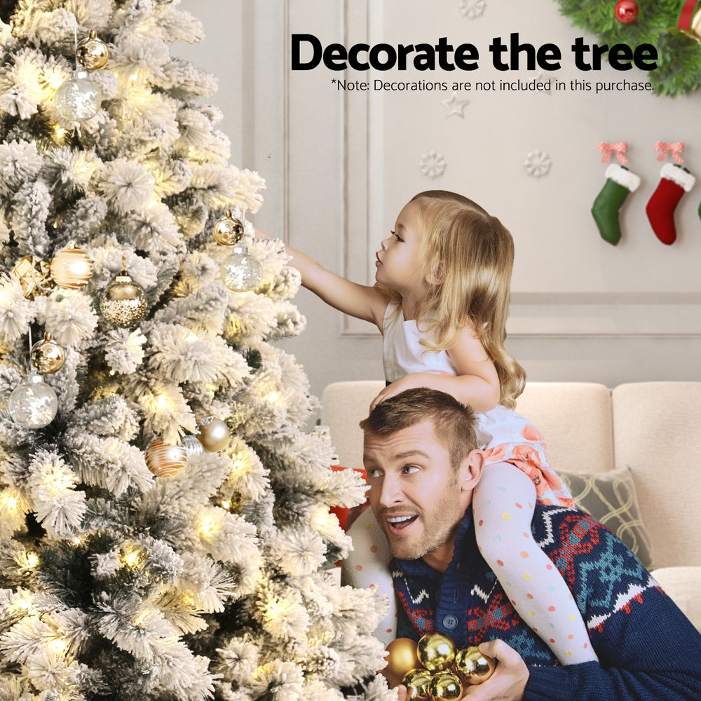 Snow-frosted Christmas tree with warm white LED lights and gold-toned bulbs