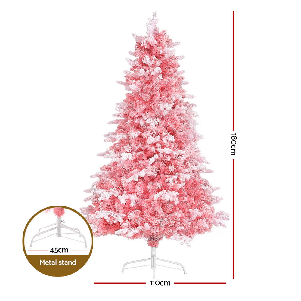 Pink snowy Christmas tree on a metal stand with full, tiered branch tips