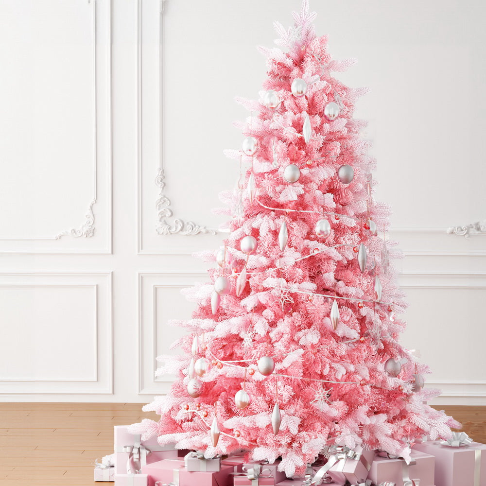 Pink snowy Christmas tree decorated with round white ornaments and garland