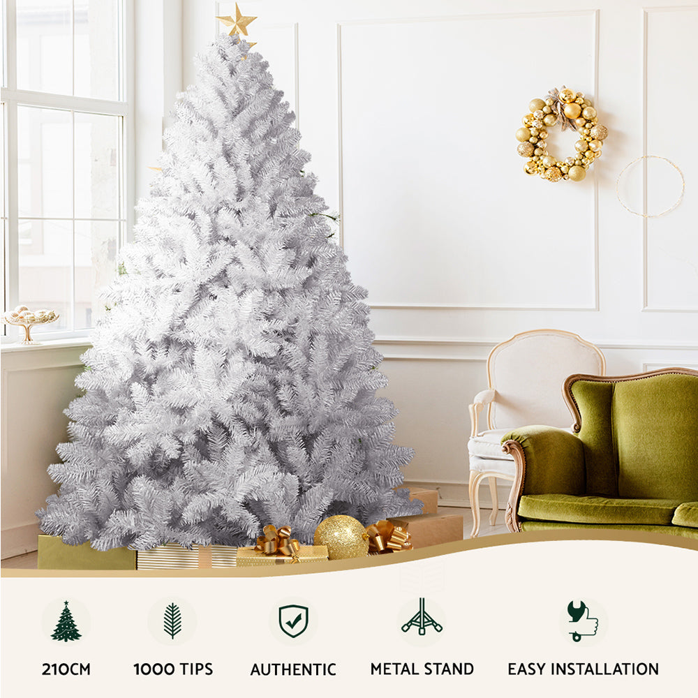 Artificial Christmas tree with white tips in a room setting, with gold-toned ornaments at the base