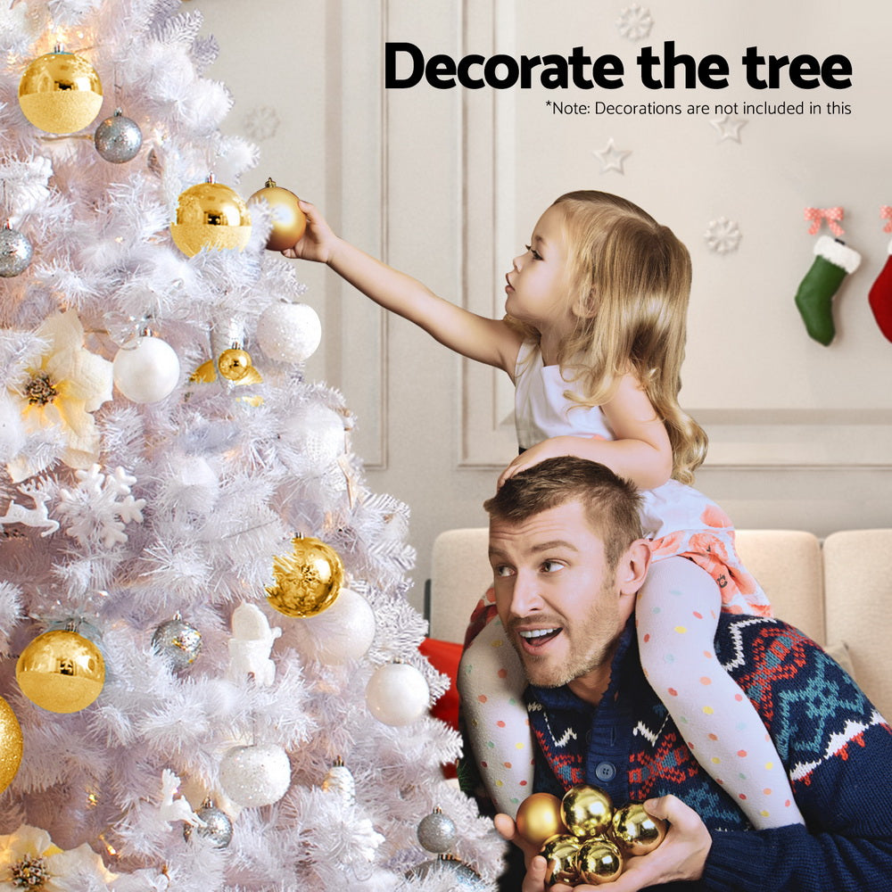 White flocked Christmas tree decorated with gold ornaments and warm LED lights