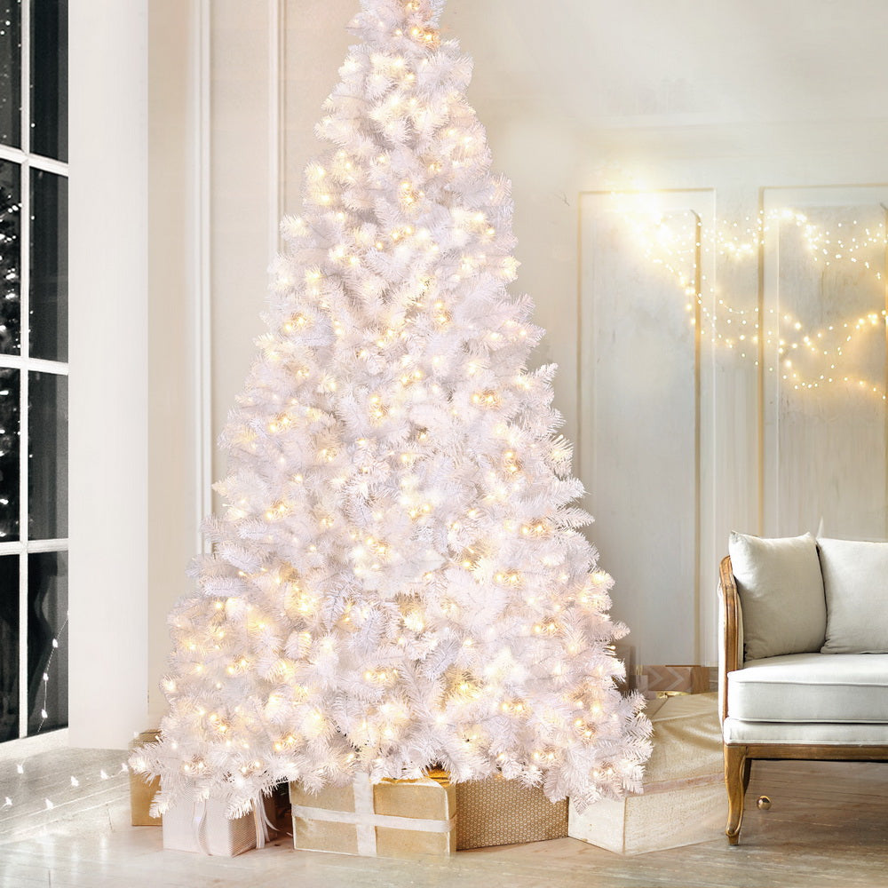 White flocked Christmas tree with warm LED lights, tall and dense, on stand