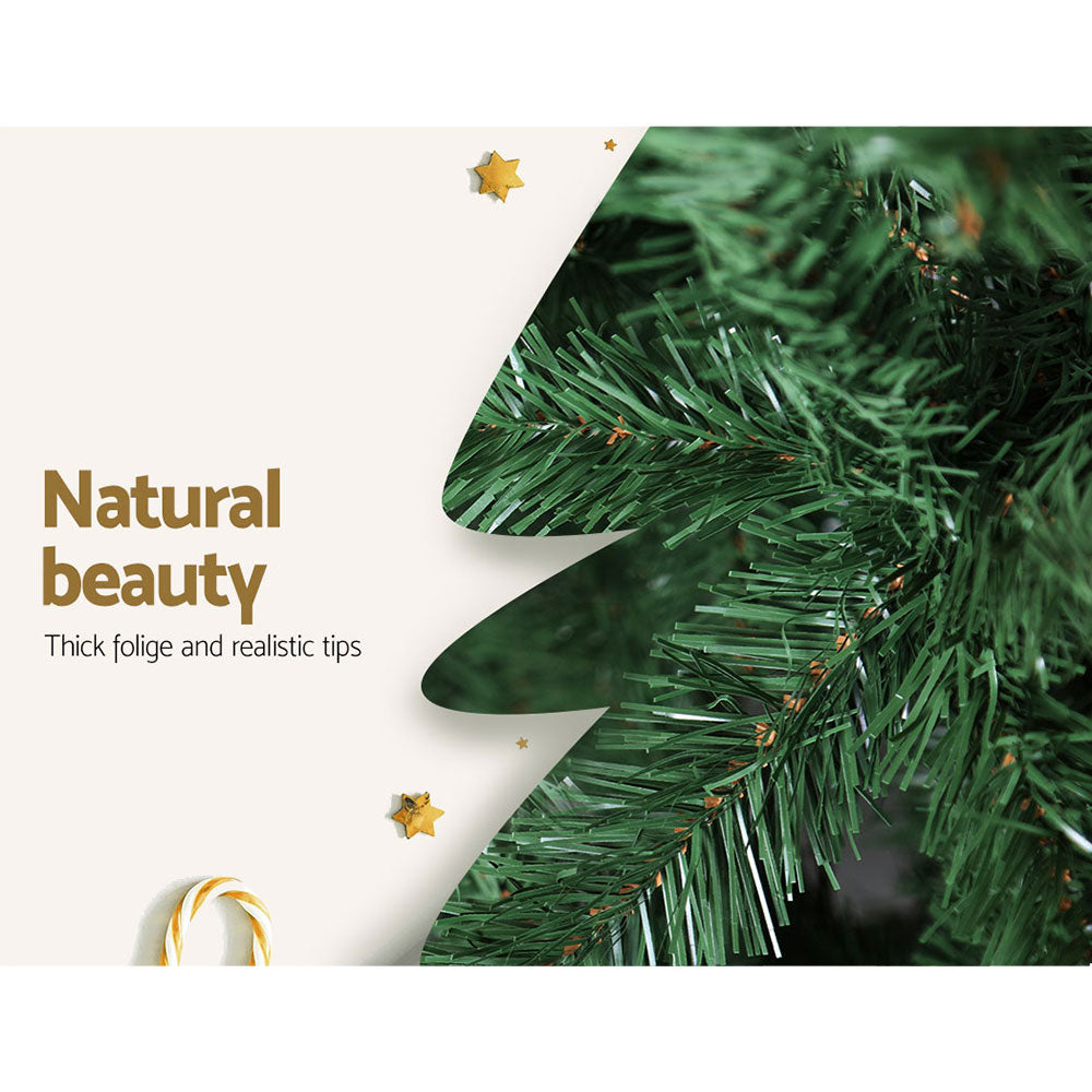 Green artificial Christmas tree with dense branch tips and small star accents