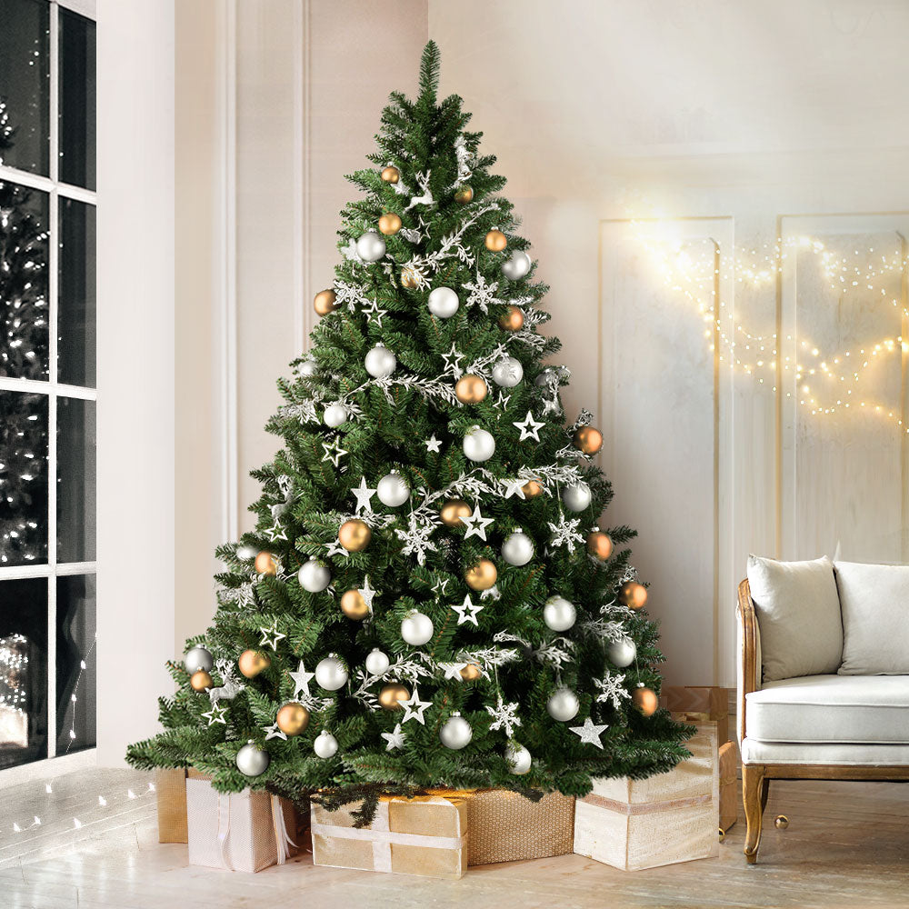 Decorated green artificial Christmas tree with white and gold ornaments and lights