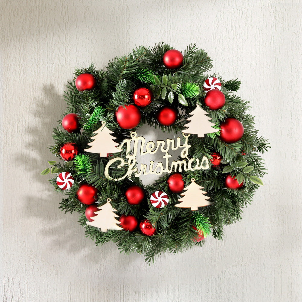 Green pine Christmas wreath with red baubles, candy cane ornaments and 'Merry Christmas' sign