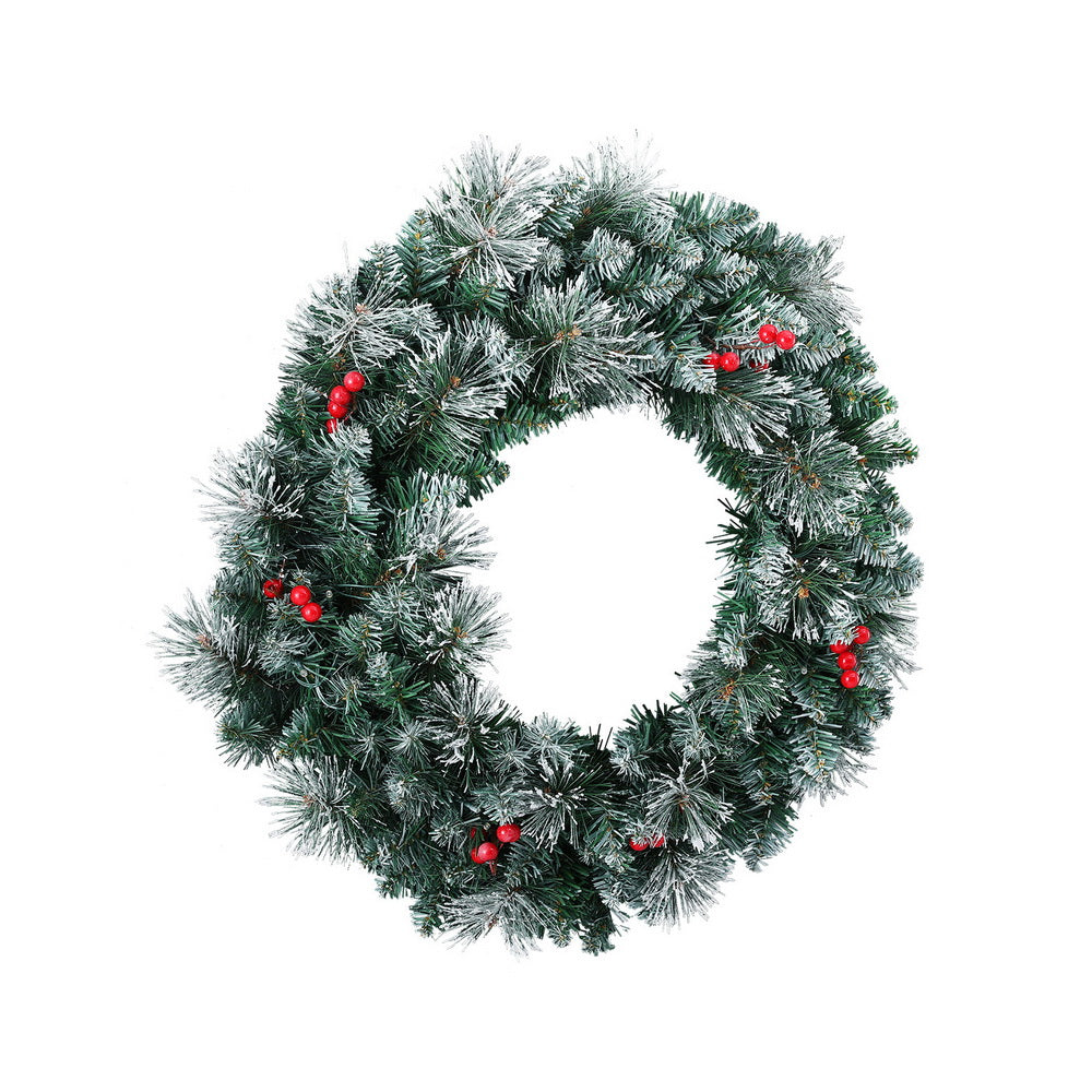 Snowy Christmas wreath with warm LED lights and red berries, partial view
