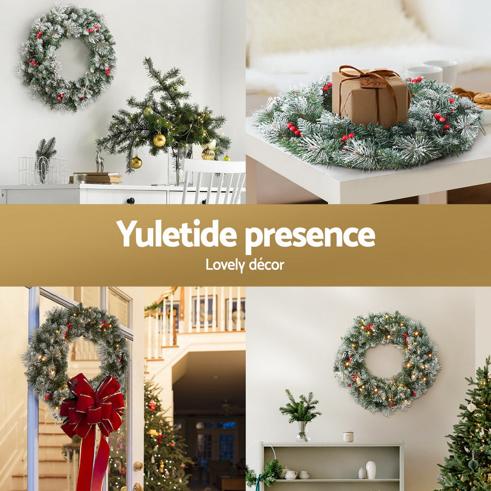 Snowy pre-lit Christmas wreath with red berries on a table decor setting