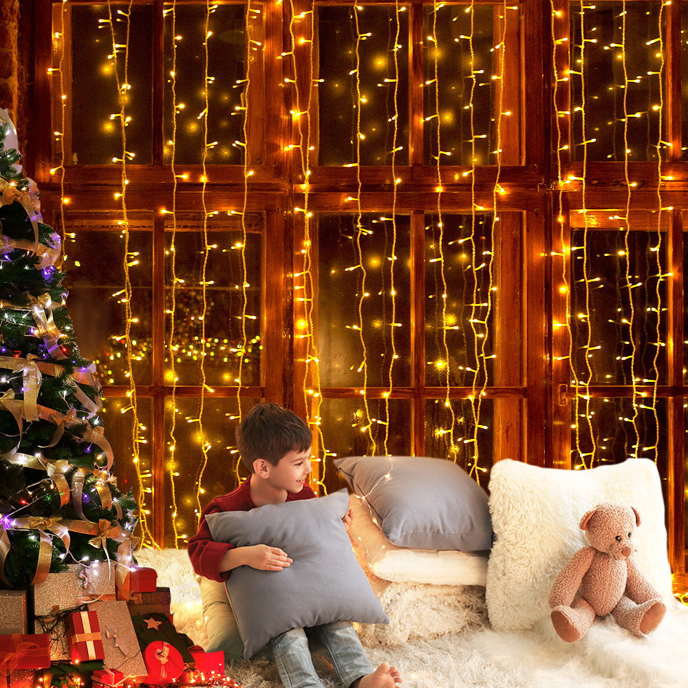 Warm white LED curtain lights strung across a wooden wall with sofa seating below