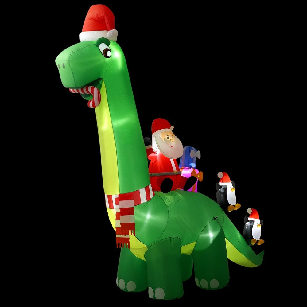Green inflatable Santa riding dinosaur with striped scarf and 3 illuminated penguin figures