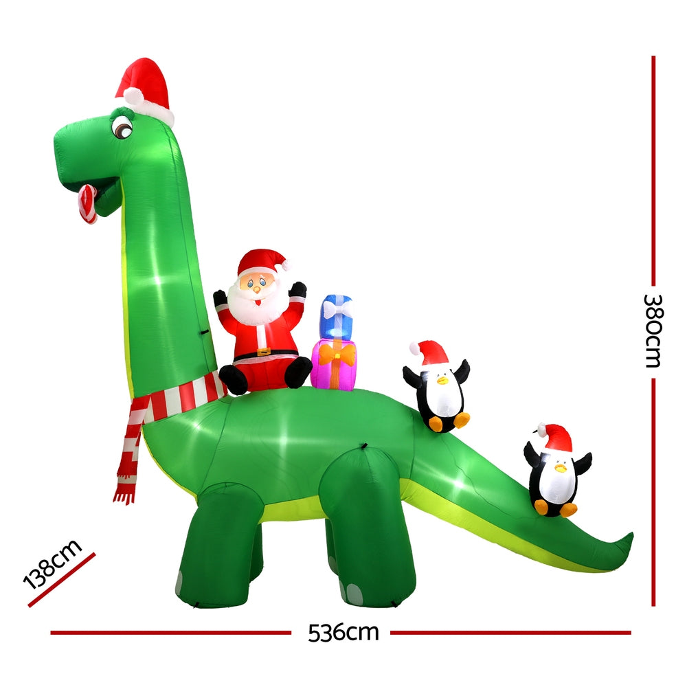 Green inflatable Santa dinosaur with three penguin figures, full standing view