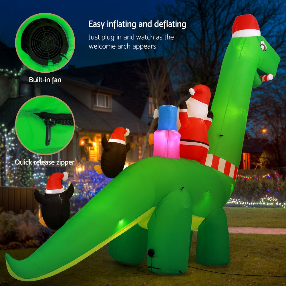 Green inflatable Santa dinosaur with penguin lights, fan and zipper features shown