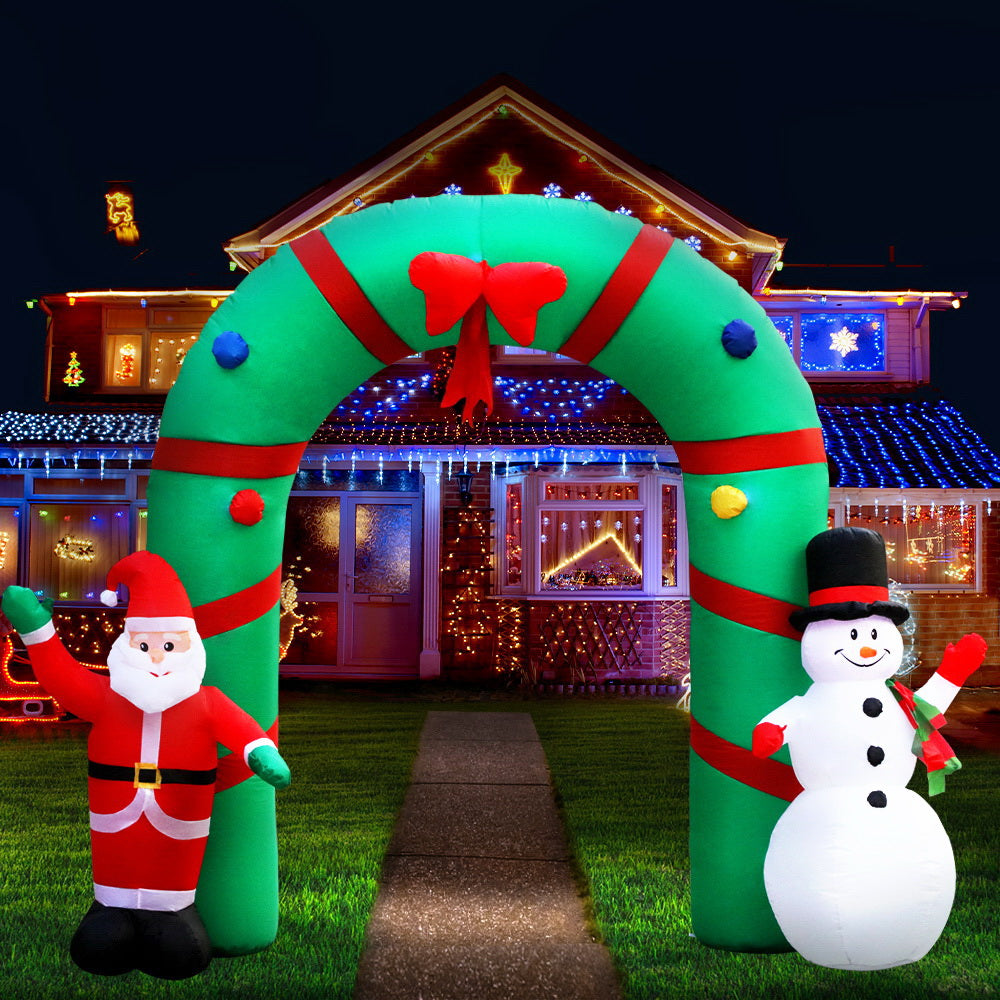 Inflatable Christmas archway with red elf and white snowman, illuminated at night