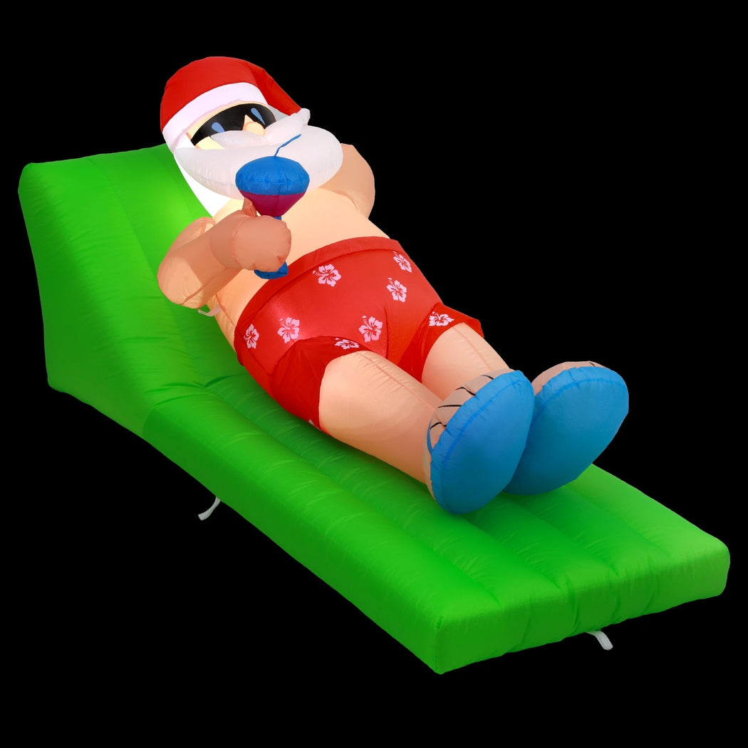 Inflatable Santa bench with Santa in red suit, white beard hat, blue boots on green air cushion.